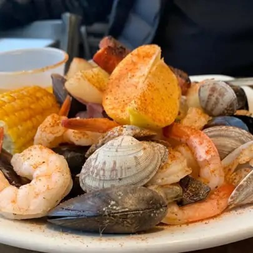 A seafood boil with shrimp, clams, mussels, corn on the cob, and lemon wedges.